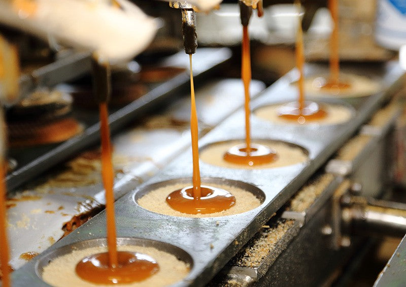 maple syrup filling being poured on waffle cookies