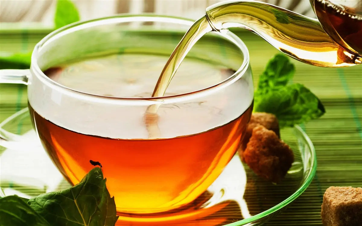 Tea pot pouring maple tea in a tea cup