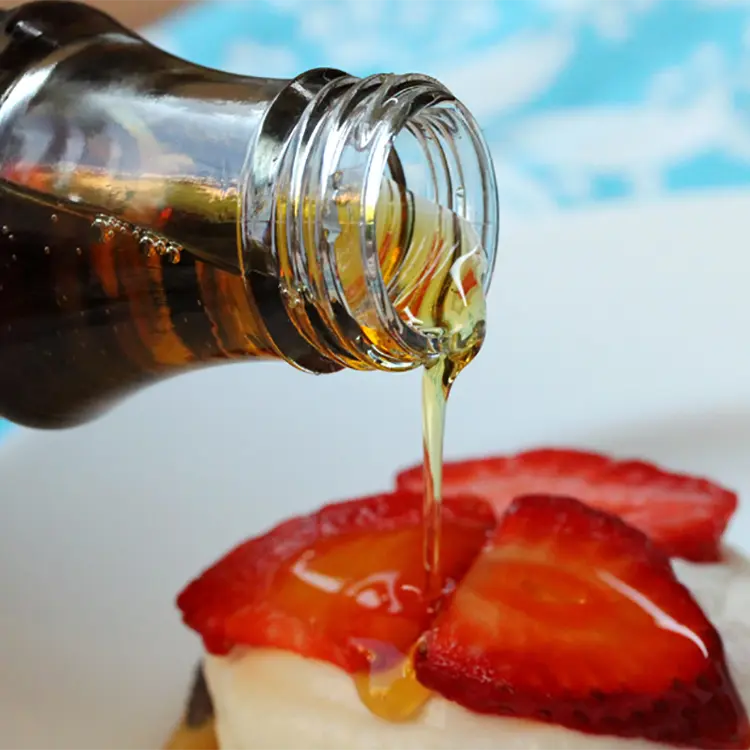 pure maple syrup poured over muffin with cream and strawberries